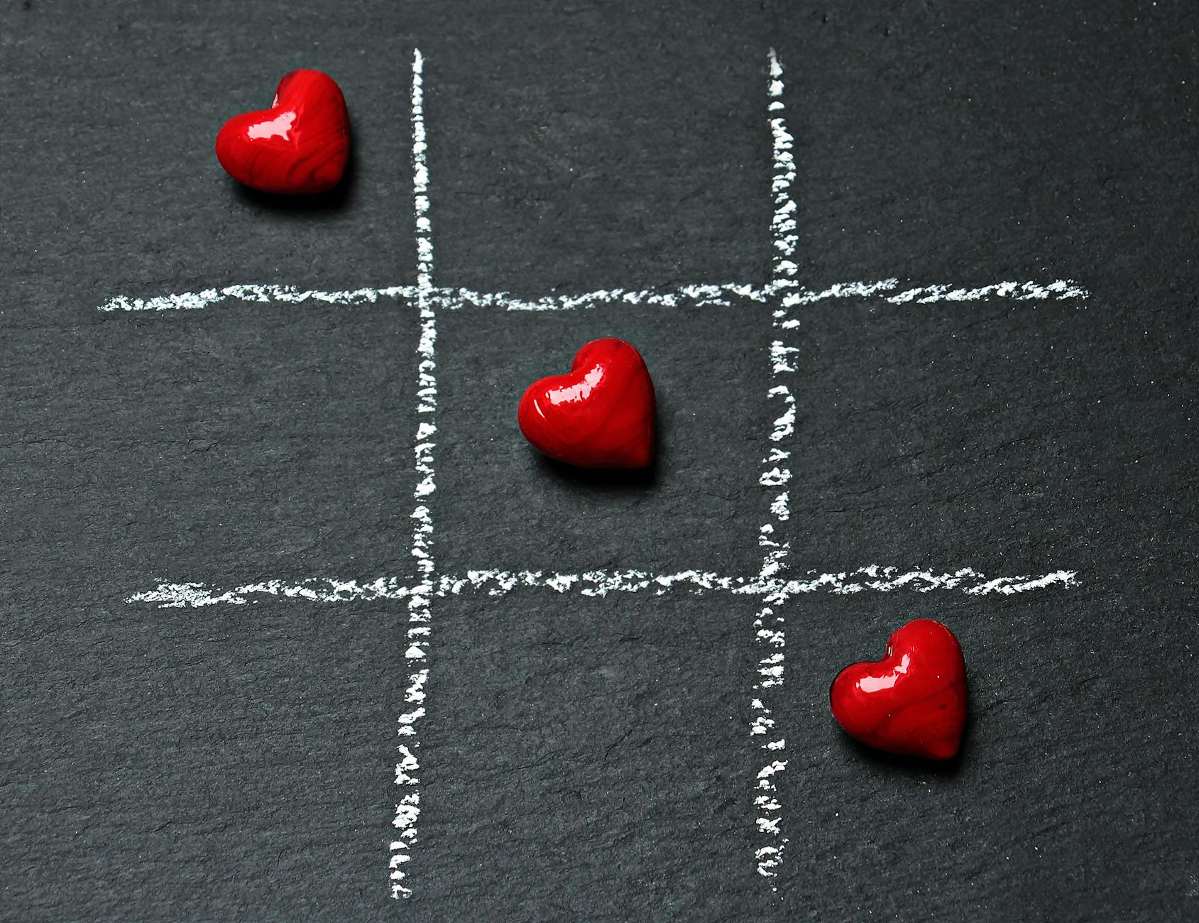 A tic-tac-toe board with three heart symbols creating a connected line from the upper left to the bottom right