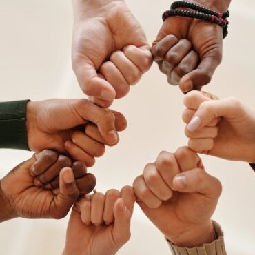A group of arms shown with them fist bumping together--connecting their hands in a circle.